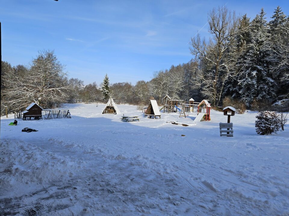 Photo représentant la cour du Vieux Moulin, avec divers éléments de parc d’amusement extérieur, sous la neige.